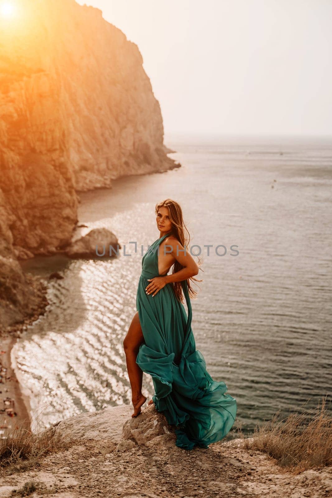 Woman sea trevel green dress. Side view a happy woman with long hair in a long mint dress posing on a beach with calm sea bokeh lights on sunny day. Girl on the nature on blue sky background