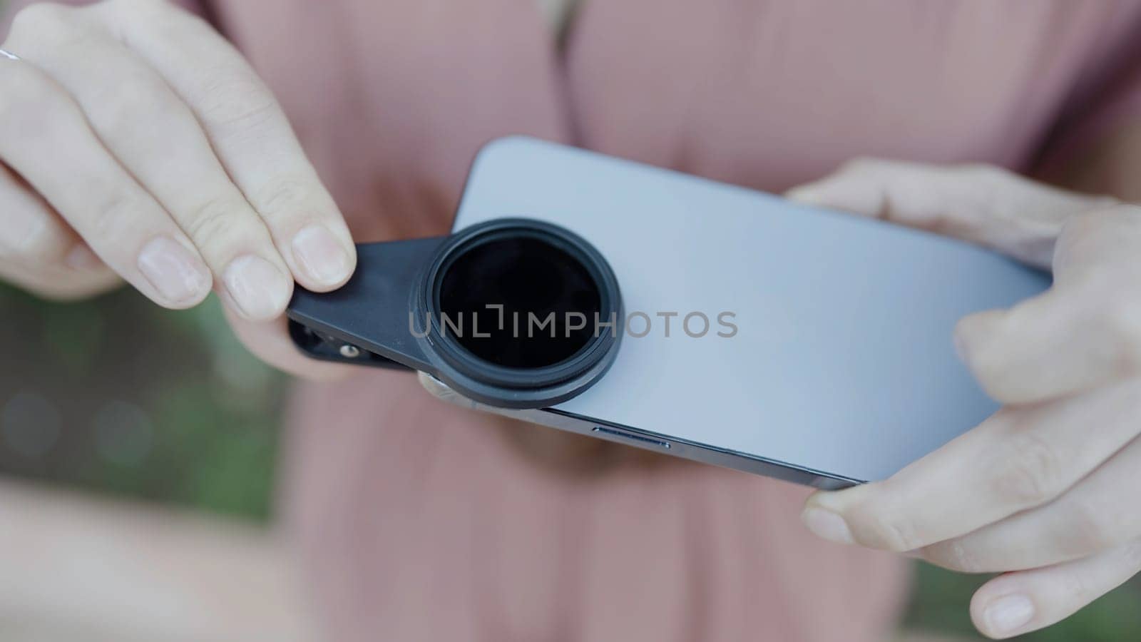Close up of woman putting removable lens for smartphone on its camera. Action. Concept of technologies