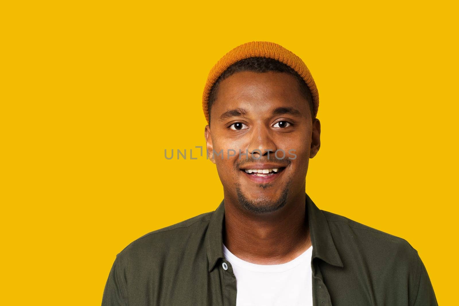 African Man Student In Basic Green Shirt Portrait Isolated On Trendy Orange-Yellow Background. High quality photo