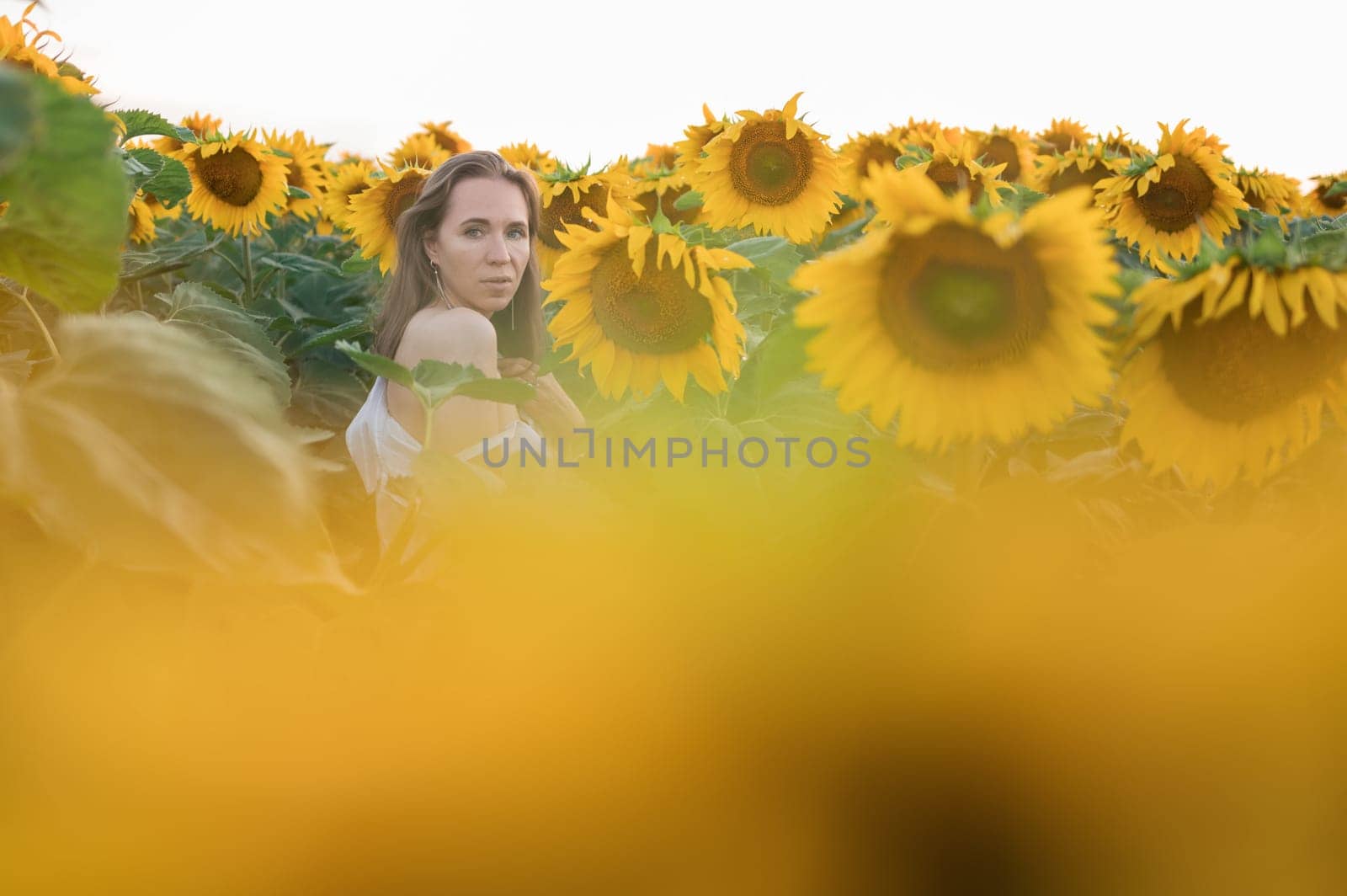 Portrait of beautiful woman posing in field with sunflowers, enjoying nature and summer.