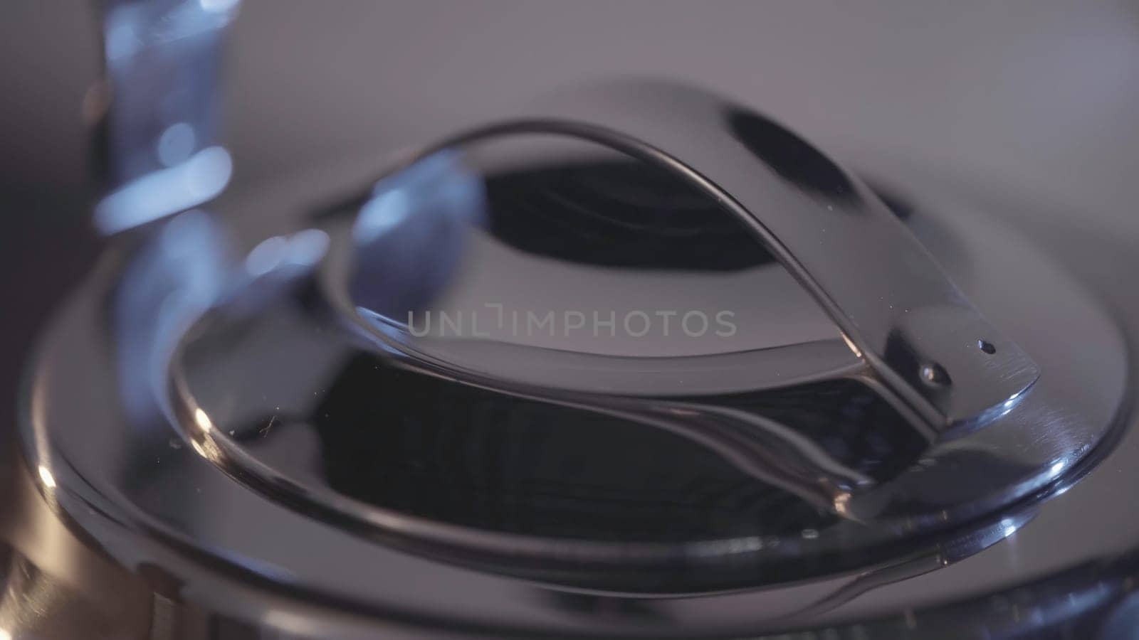 Lid of metal teapot. Action. Close-up of beautiful metal parts of kettle. Stylish Steel Kettle for boiling Water. Shiny details of new metal teapot.