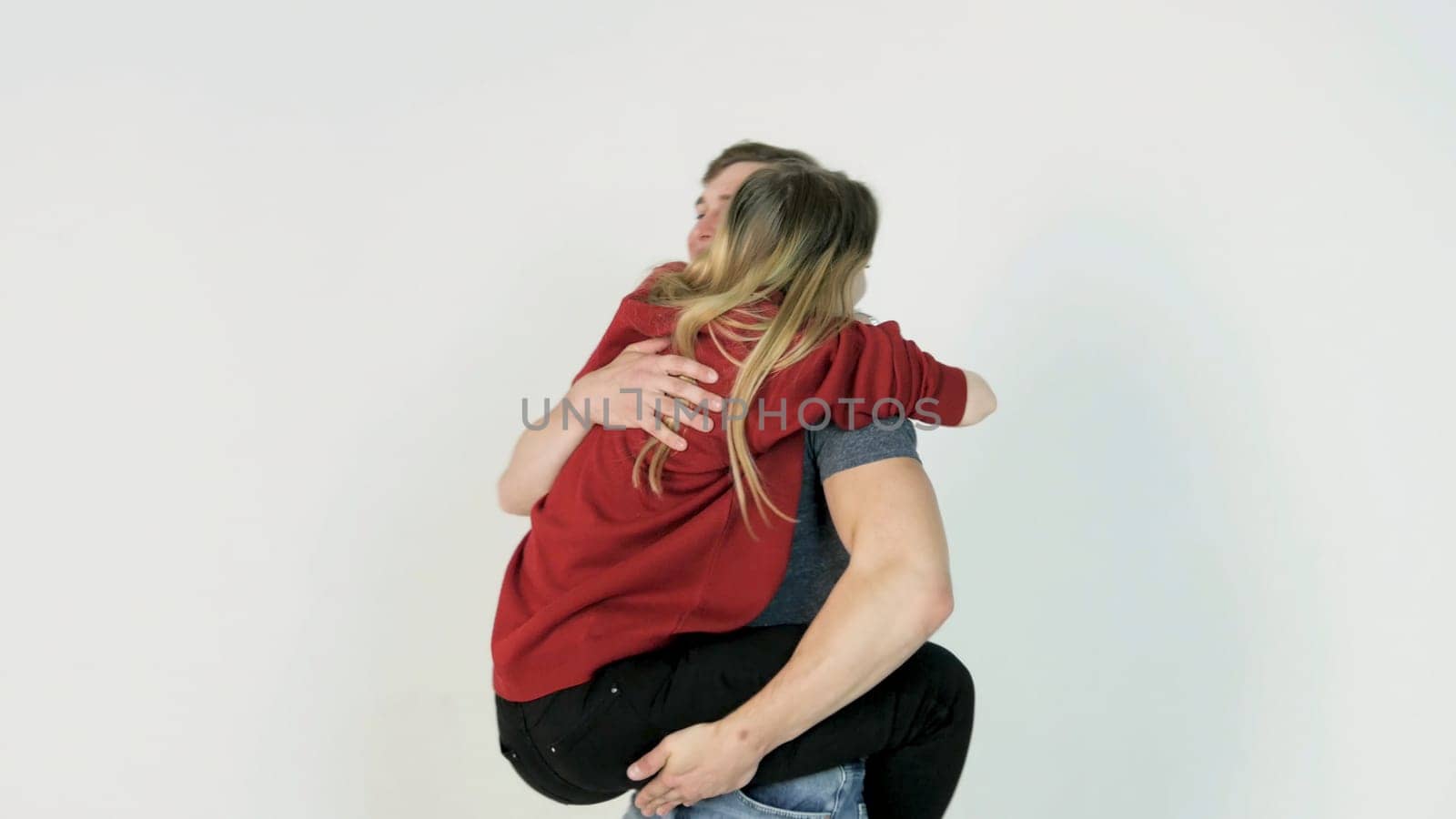 Guy turns the girl on hands. Young man turns the girl on hands on white background.
