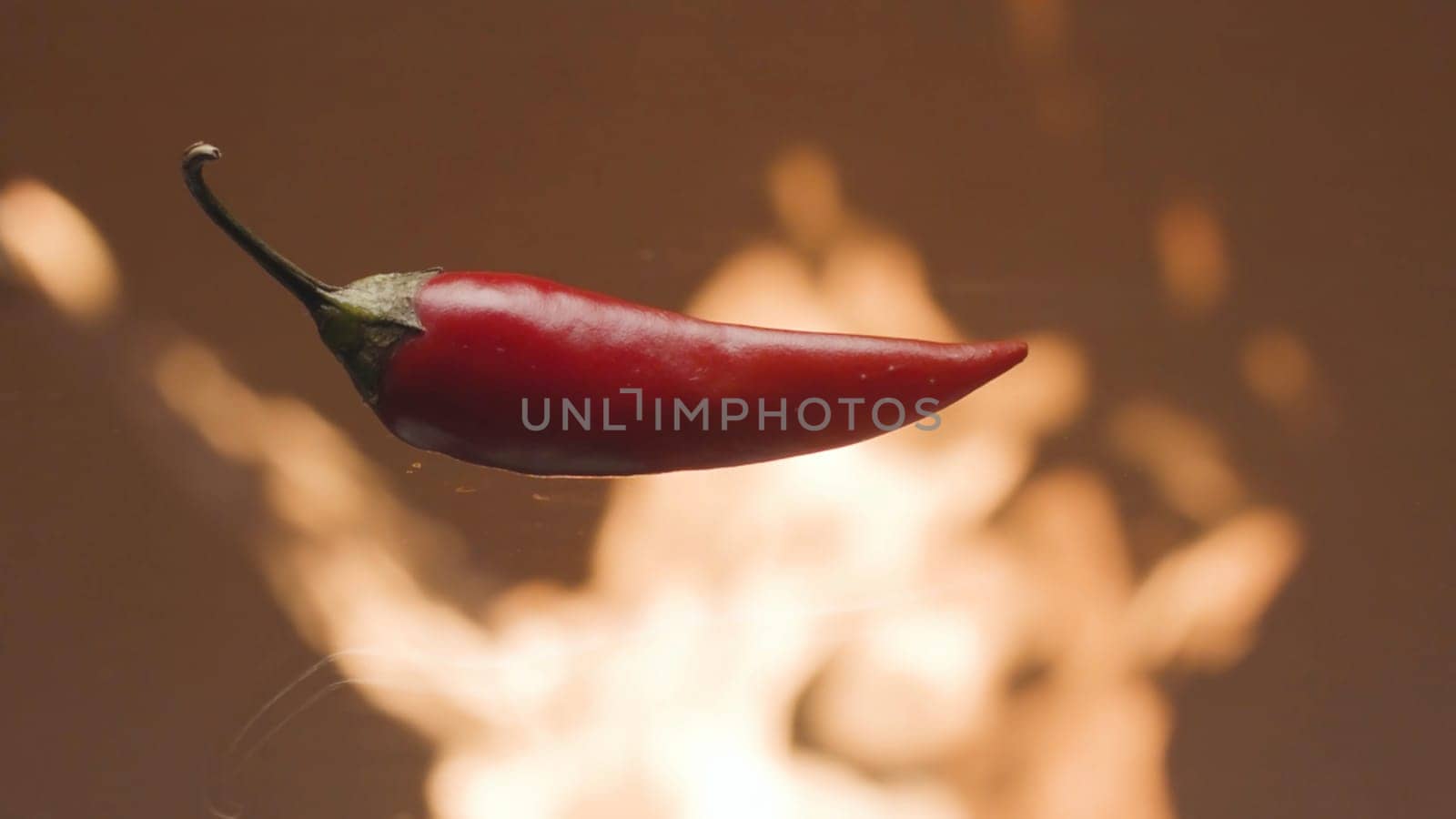 Close-up of red pepper on background of fire. Stock footage. Hot red chili pepper on background of flame of fire. Chili pepper burning like flame of fire. Promotional video with hot pepper.