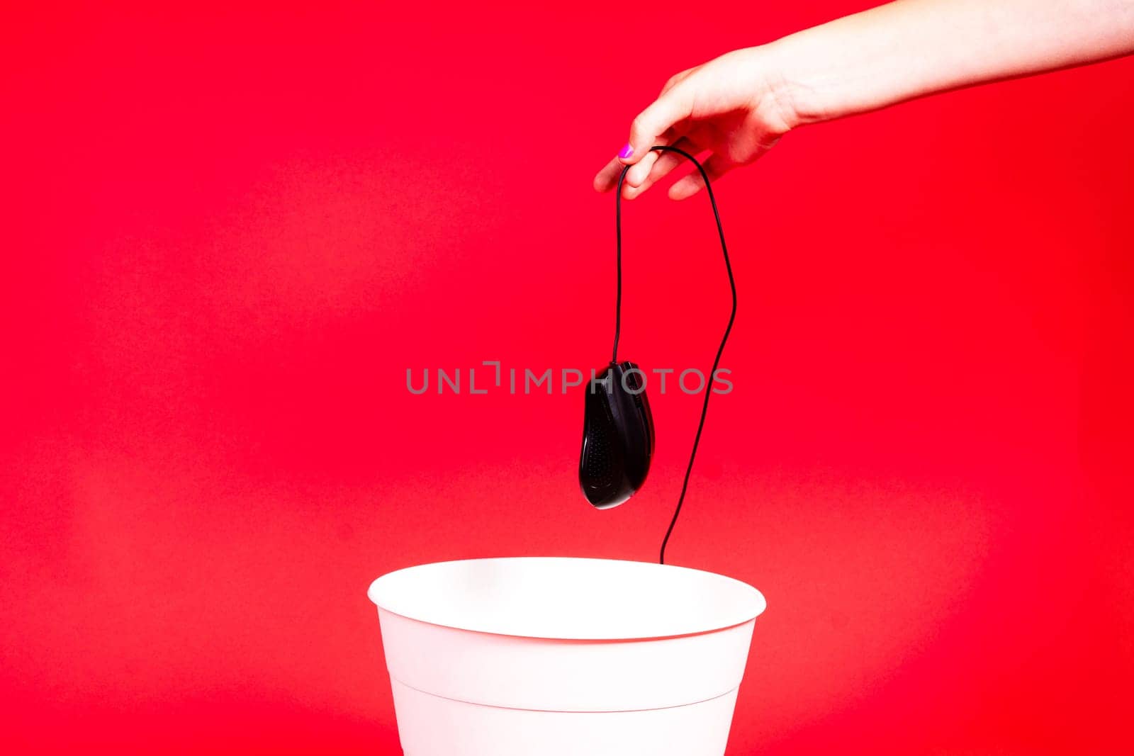 A computer mouse with a wire is thrown into a office wastebasket.