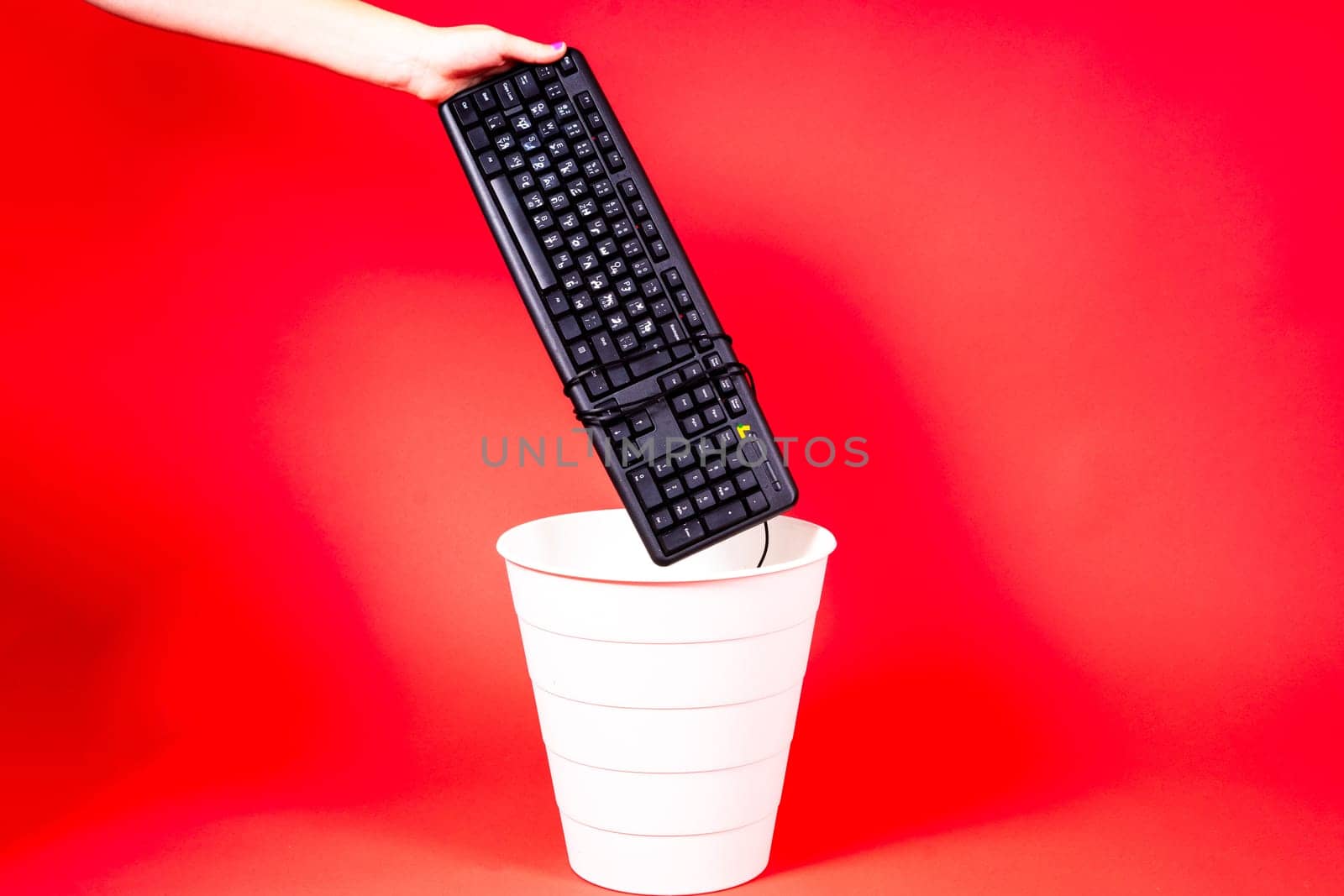 Woman putting a computer keyboard in a e-waste trash bin, recycling concept