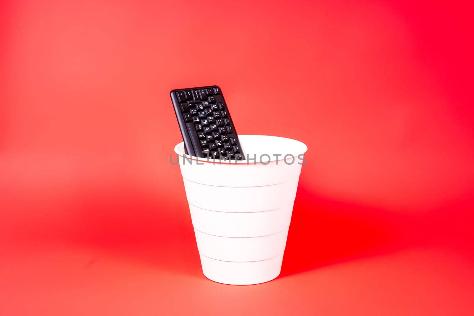 Woman putting a computer keyboard in the e-waste trash bin, recycling concept by Zelenin