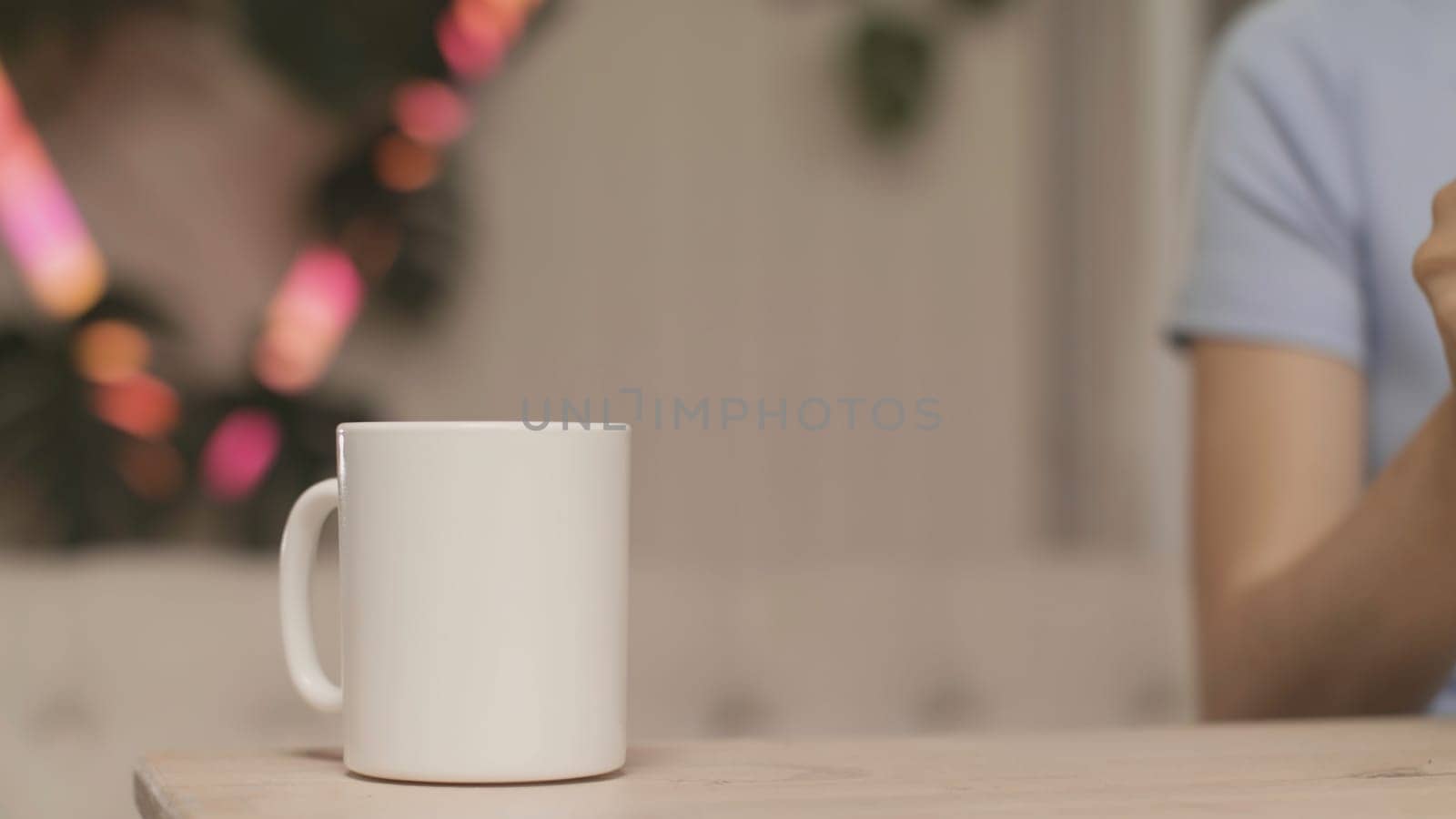 Close-up of women's hands pouring tea on background of lights. Stock footage. Young woman makes herself cup of tea. Woman makes tea on background of blurred lights.