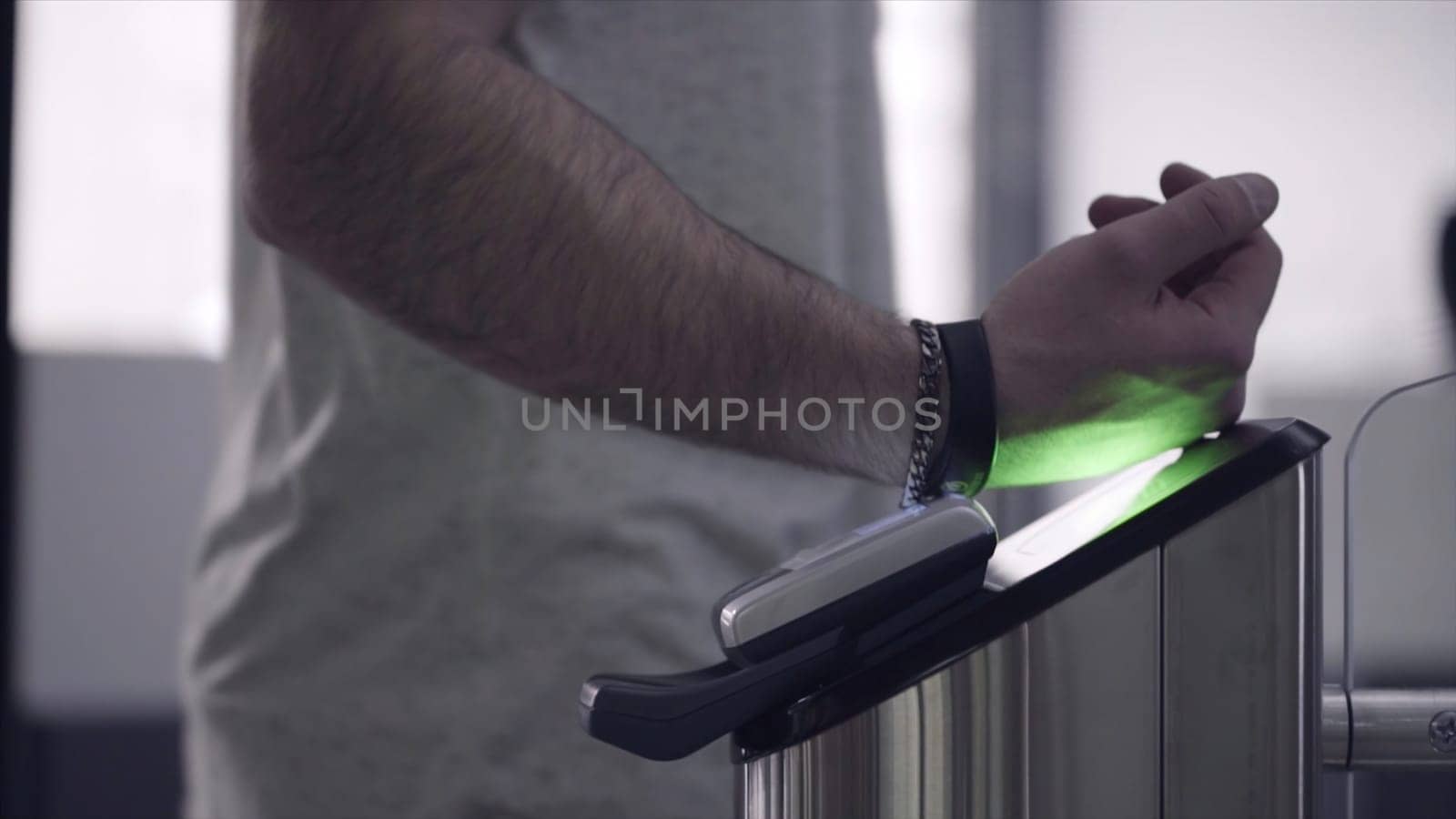 Close-up view to turnstile. Frame. Electronic access control security system indoor side view. Close-up view of hand of man applying pass to turnstile.