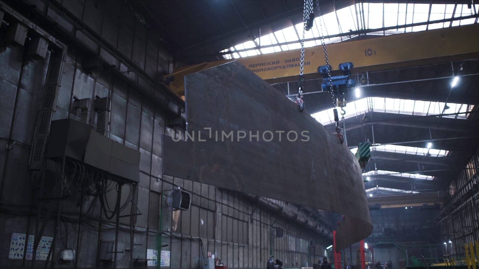 Metal frame hanging on chains in factory. Clip. Large metal panel suspended on chain in factory warehouse. Transfer of metal panels on circuits in plant.