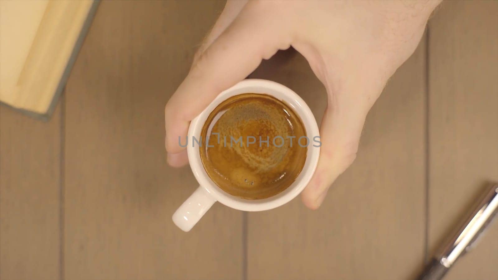 Human Hand Holding Coffee Cup Morning Drinks. Male moves a Cup of coffee. Cup of coffee with flowing milk on wooden background HD