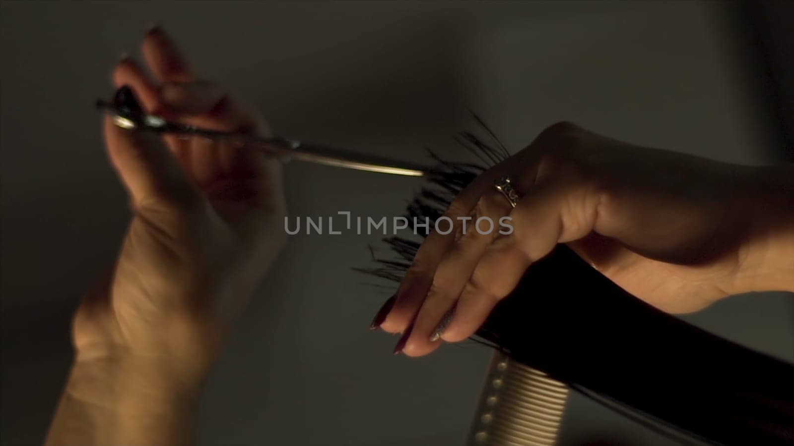 Scissors cut the girls hair. Frame. Hairdresser trimming brown hair with scissors. Professional stylist cutting woman's hair in salon, closeup. Close up of hairdresser cutting the hair.