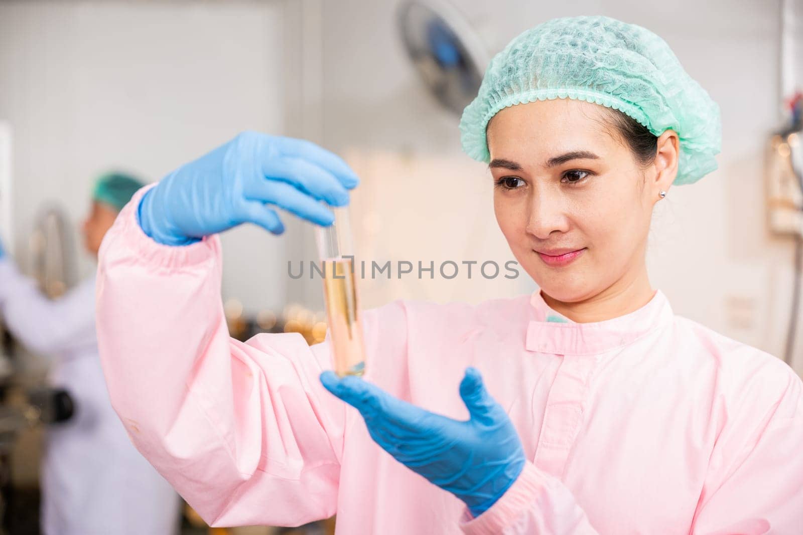 Within juice beverage factory woman food engineer illustrates food and beverage quality and safety testing using test tubes for sampling basil or chia seeds in bottled products emphasizing expertise