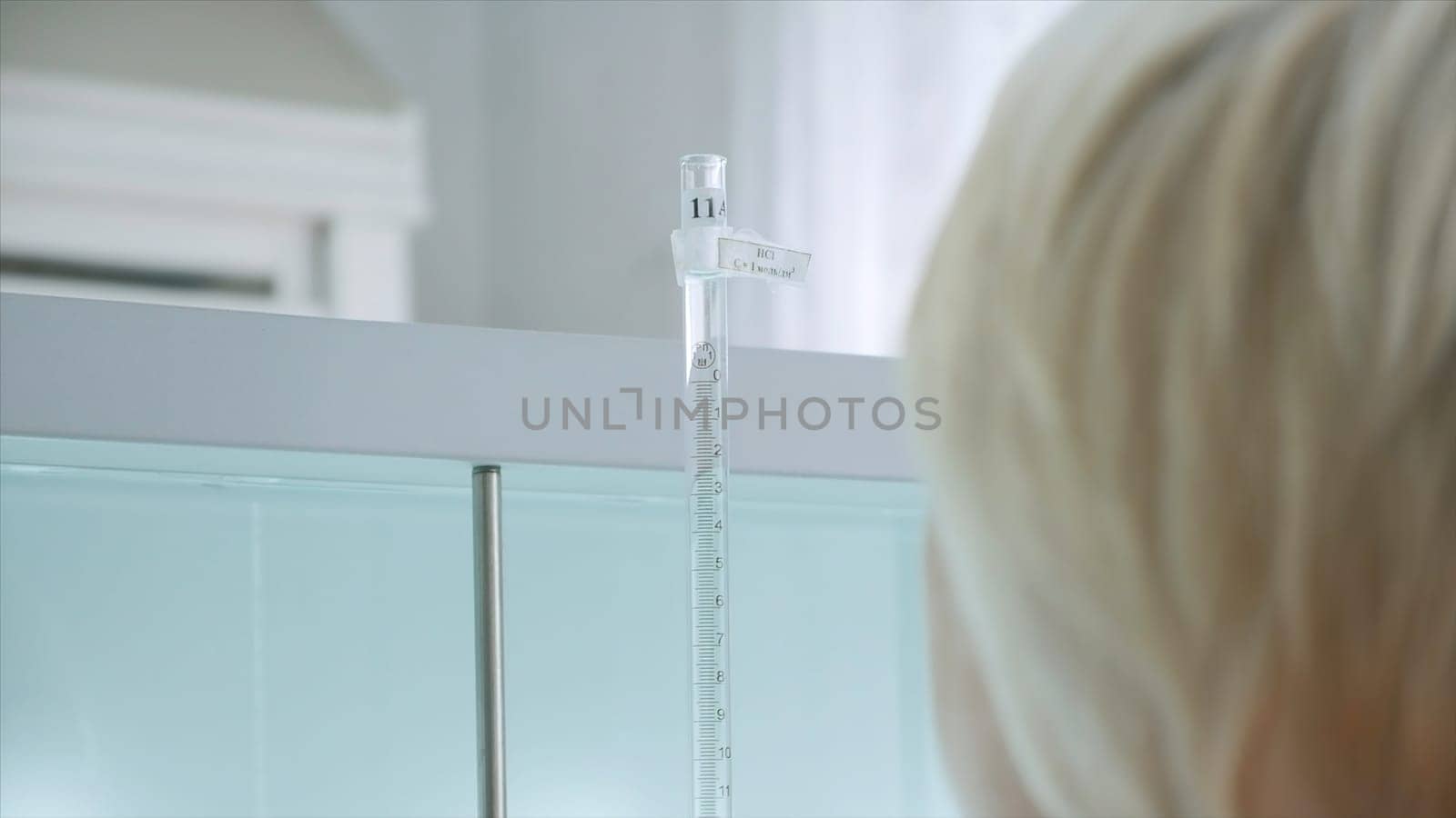Woman conducts laboratory experiments and analyzes. Clip. Woman looks at chemical liquid in laboratory. Industrial laboratory with workers and chemicals in test tubes.