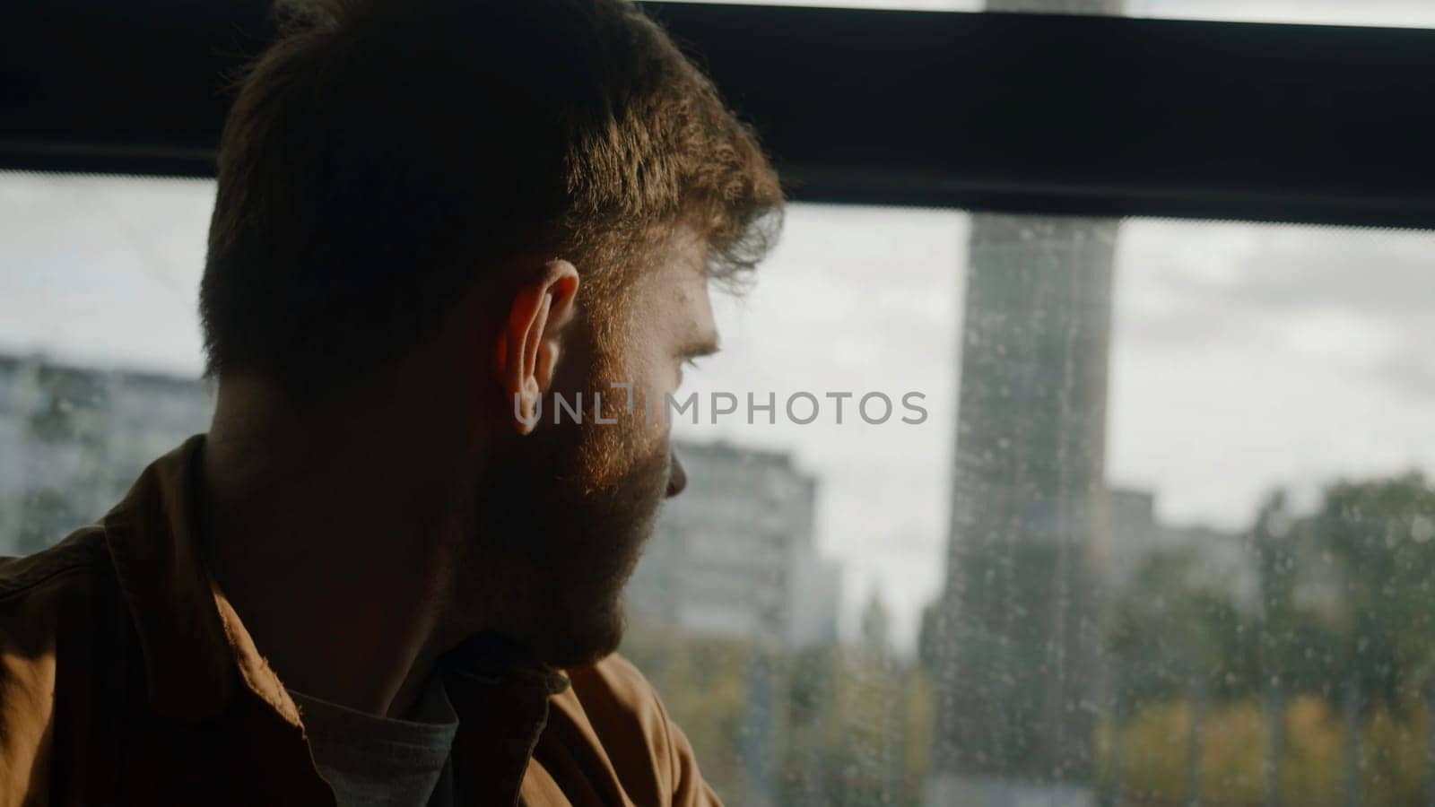 A beautiful portrait of a man. Stock footage. A man on a bus looks at the rays of the sun near the park. High quality 4k footage