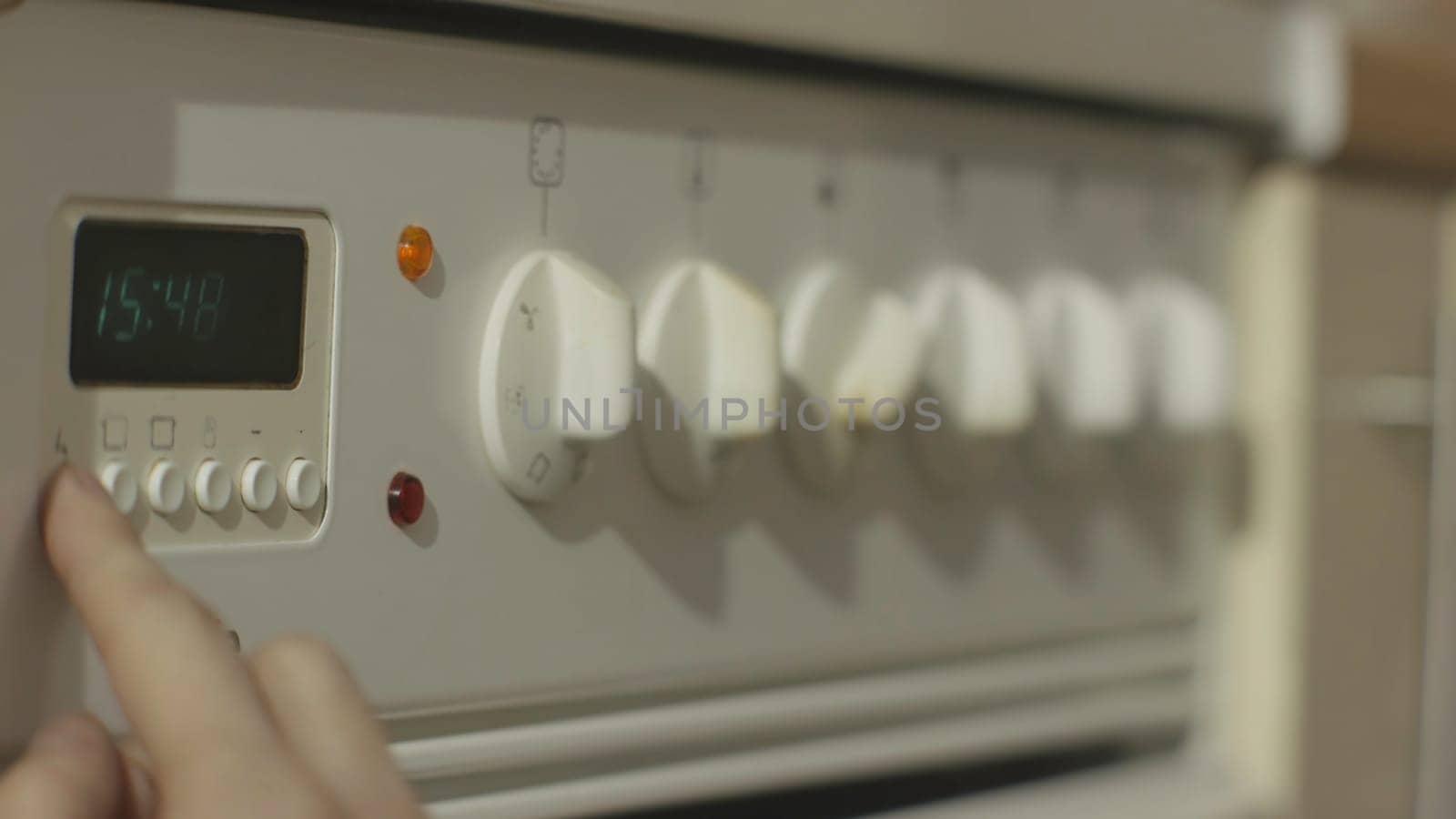 Female hand turning on white kitchen gas stove. Woman turn on the stove in the kitchen close up 4K