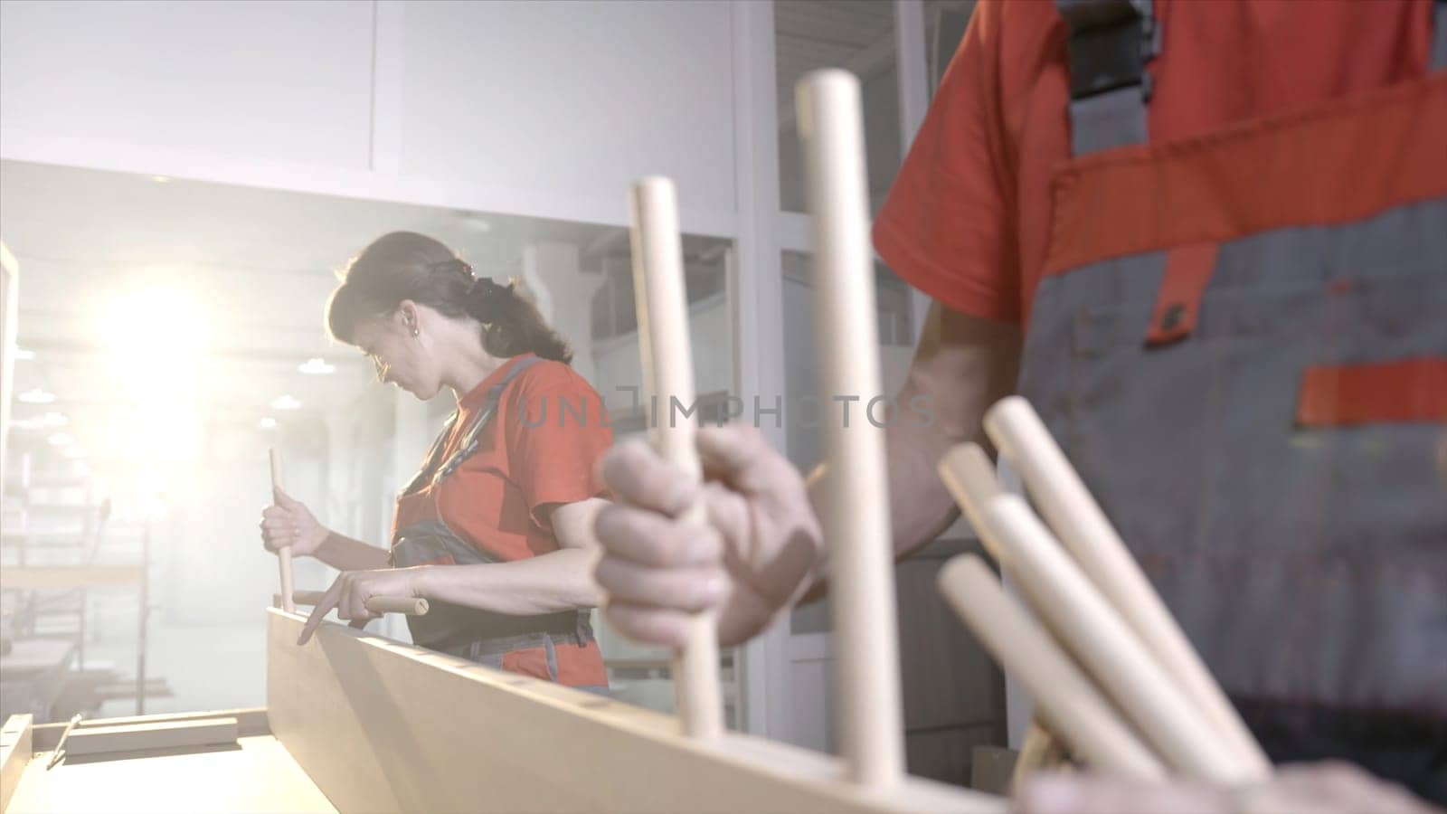 Wooden furniture mounts. Action. Close-up workers put wooden dowels in frame. Connection of wooden furniture details. Fixing furniture with round wooden sticks.