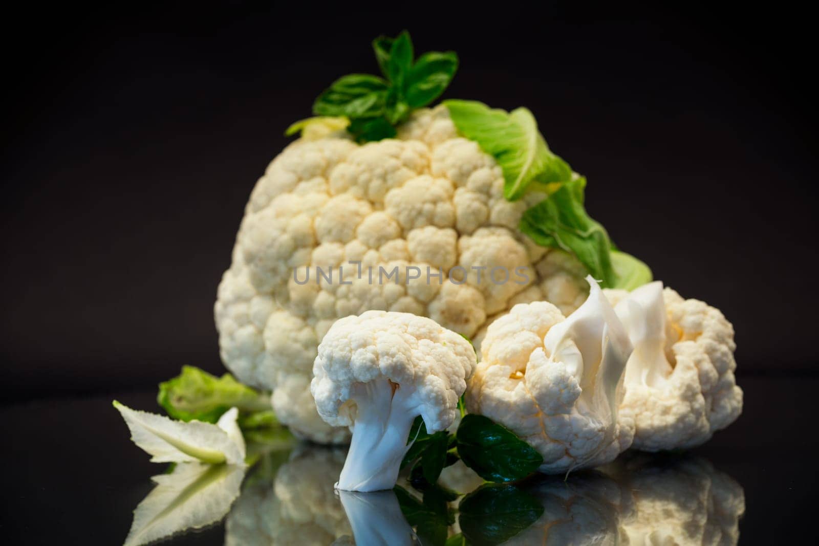 slices of raw small raw cauliflower on black background by Rawlik