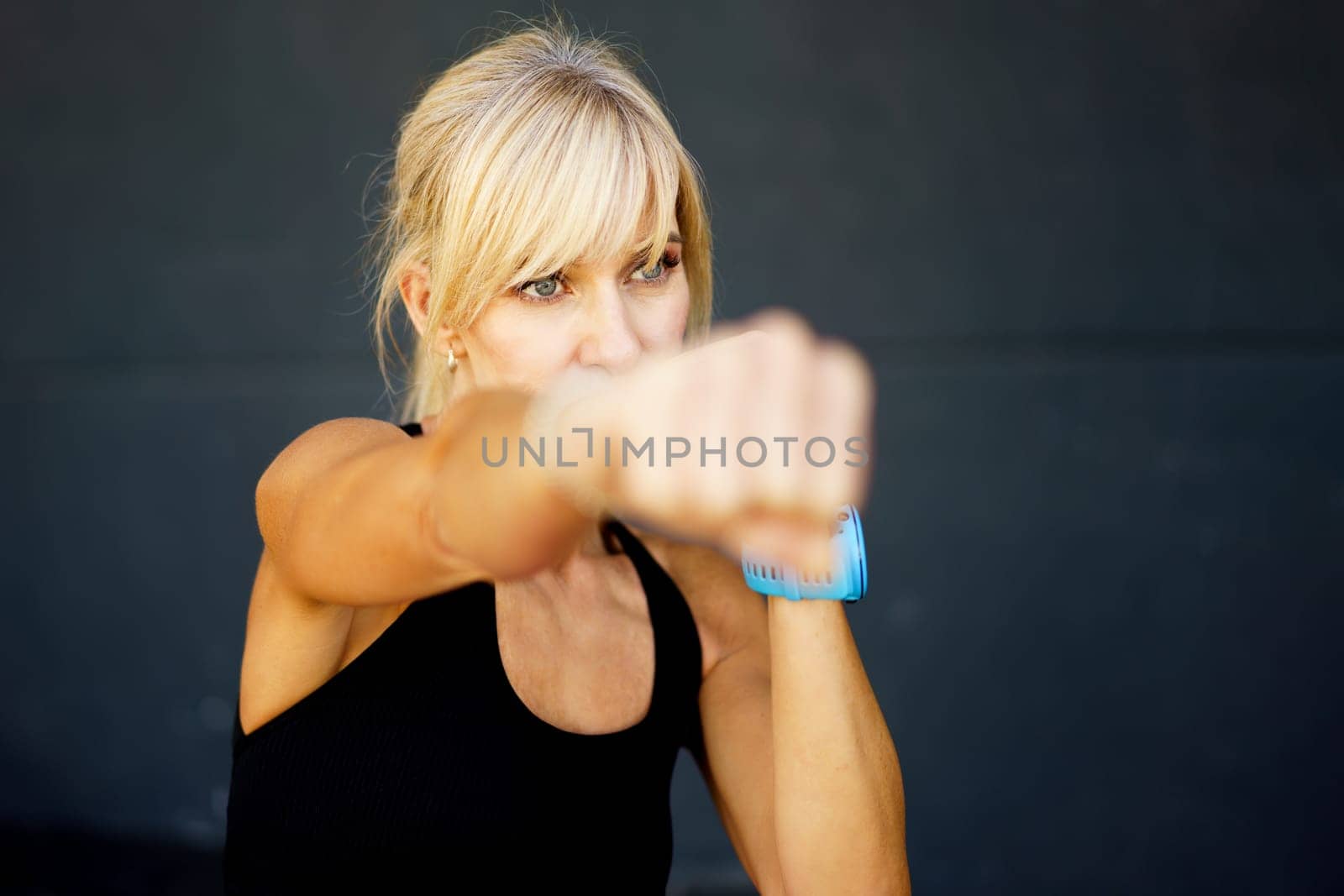 Focused Young female fighter performing martial art punches in fitness studio by javiindy