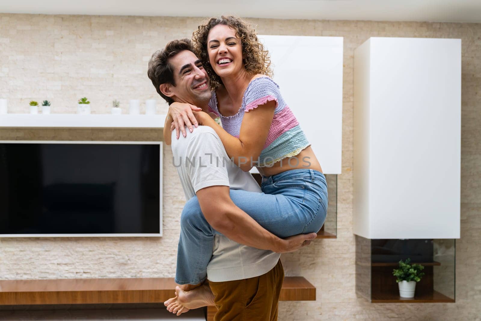 Smiling couple hugging in modern apartment at home by javiindy