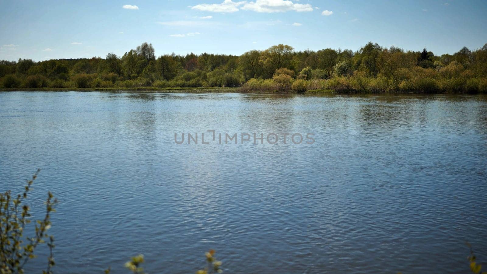 Reflection in the Neman River of cumulus clouds and the river bank overgrown with bushes and trees. Belarus region