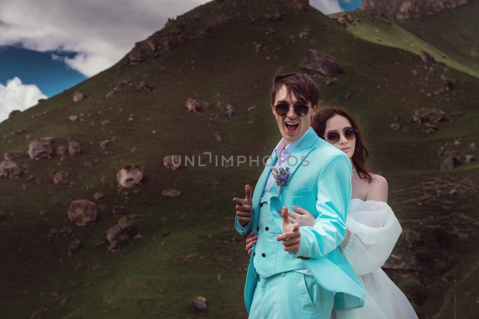 wedding couple hugs and looks at the camera, cheerful groom jokes. photography in the mountains in summer, close-up.