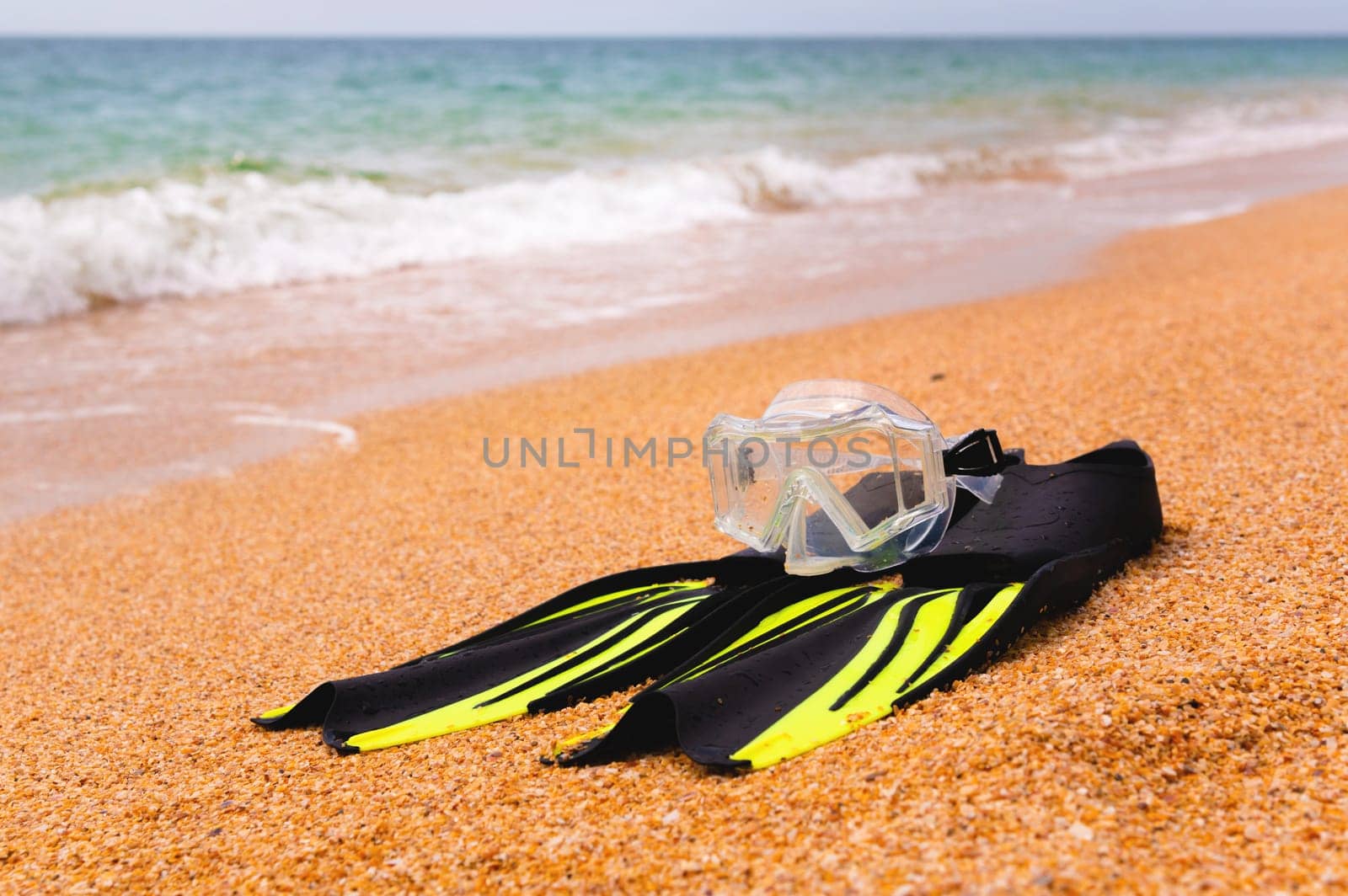 pair of fins and a diving mask on a sandy beach, bottom view. Space for text or advertising of a sports store or beach resort by yanik88