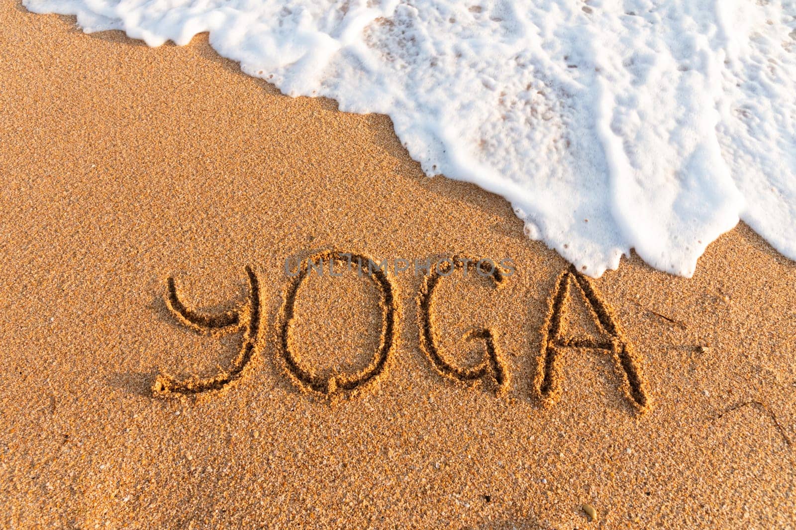 The inscription yoga on the sea sand, the concept of a wellness tour. sea with sand, top view, inscription by yanik88