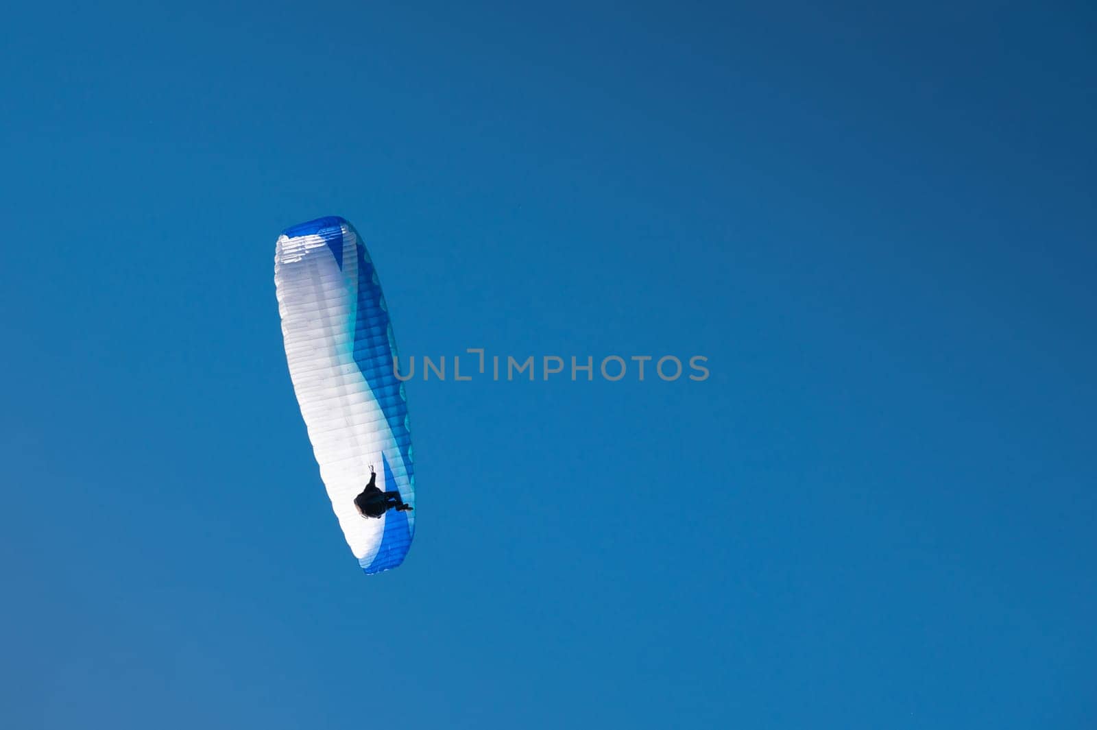 paraglider flies in the blue sky. athlete flying in the air, piloting on wind currents.