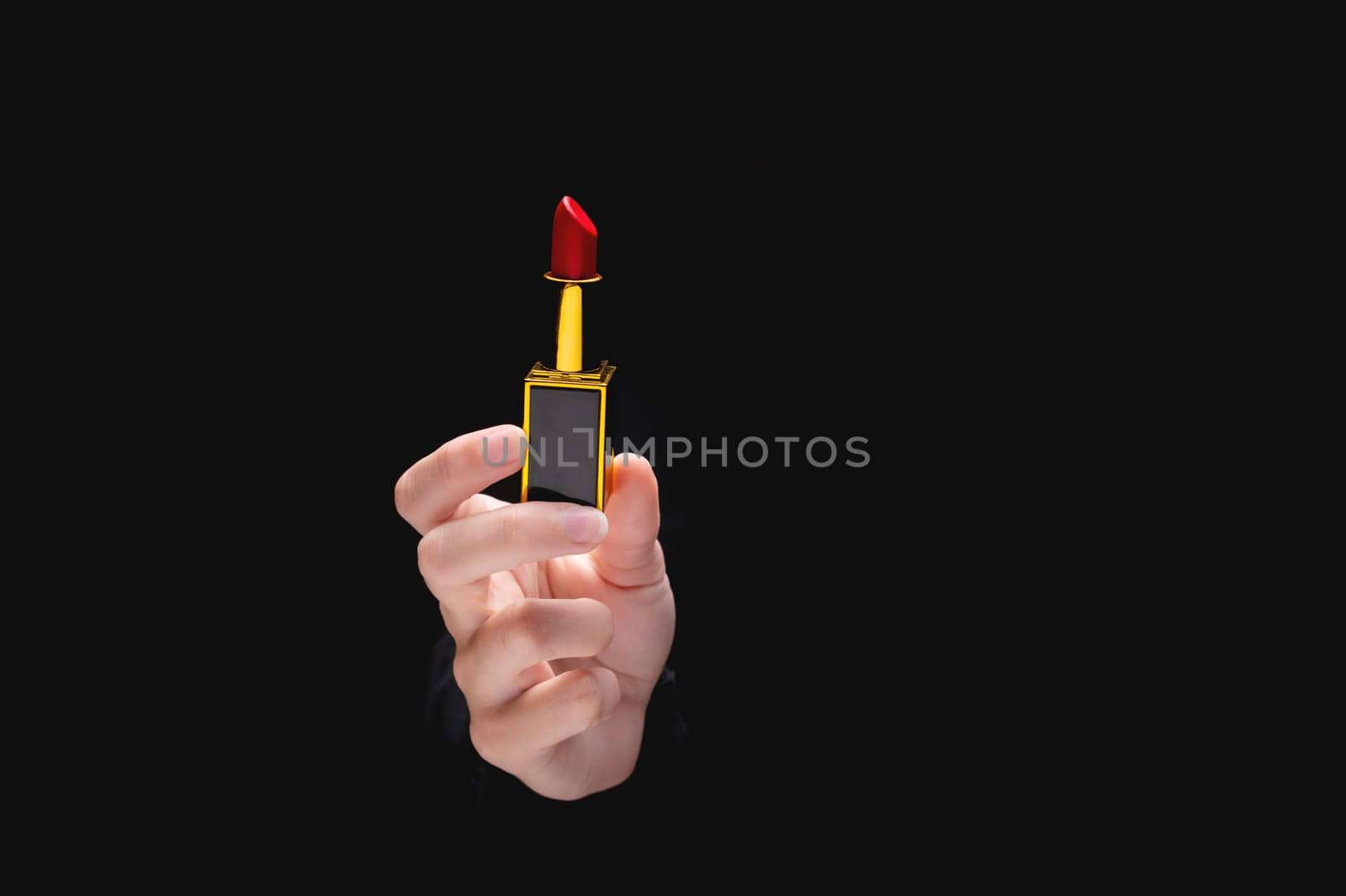 Red lipstick in a woman's hand on a dark background. Girl holding a popular cosmetic product by yanik88