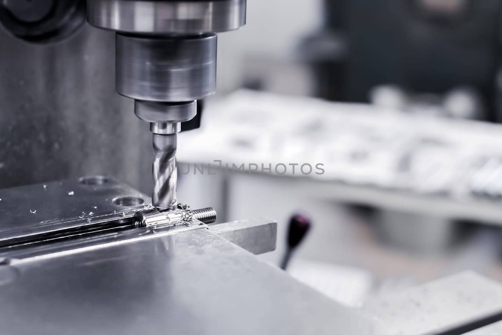 In production, a drill drills into an aluminum steel plate with a drill. A metal drill makes holes in a steel workpiece on an industrial machine. Metalworking industry. Close-up.