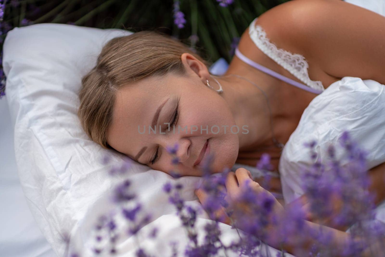 A middle-aged woman lies in a lavender field and enjoys aromatherapy. Aromatherapy concept, lavender oil, photo session in lavender by Matiunina