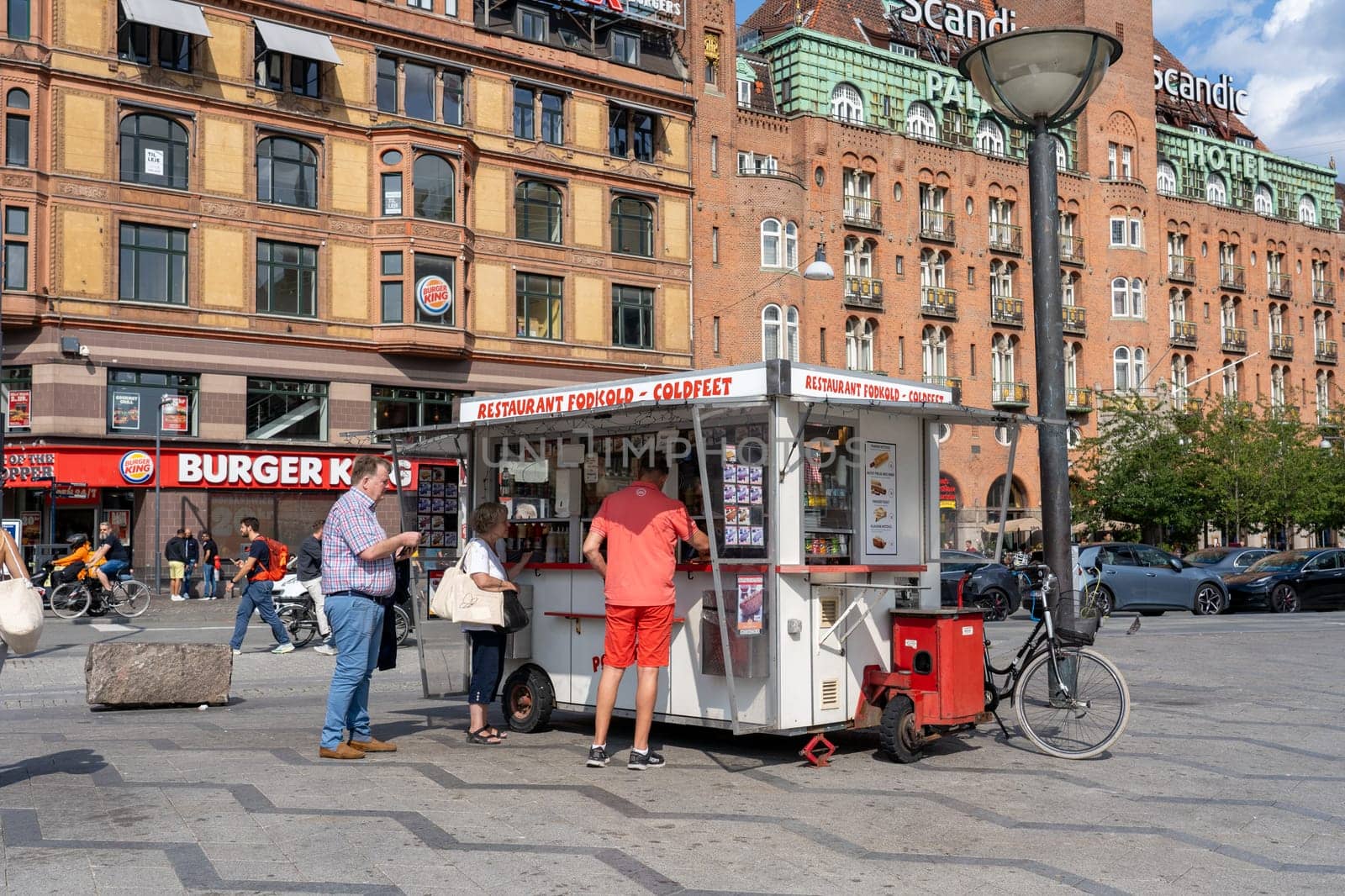 Copenhagen, Denmark - July 14, 2023: Customers at a traditional hot dog cart on the town hall square.