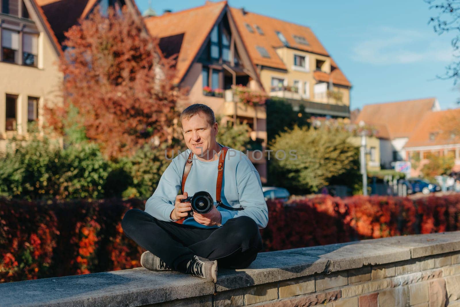 Man Sitting on Stairs in Old European City And Holding Photo Camera. Contemporary Stylish Blogger And Photographer