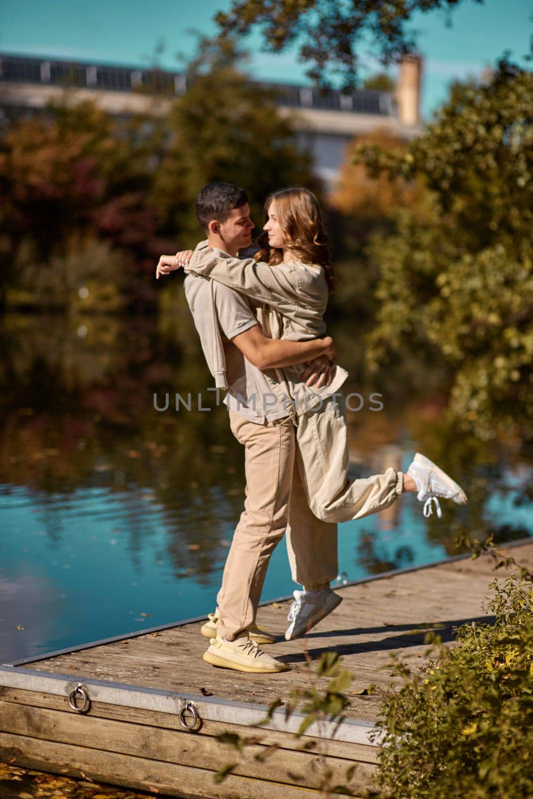 A guy carrying a girl on his back, at the beach, outdoors. River. Young Girl And Guy Love. Handsome young man kissing his girlfriend near the river by Andrii_Ko