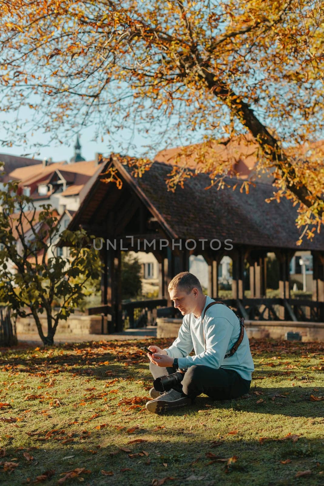 Professional photographer taking picture of beautiful autumn park. man professional photographer sit with camera in autumn park