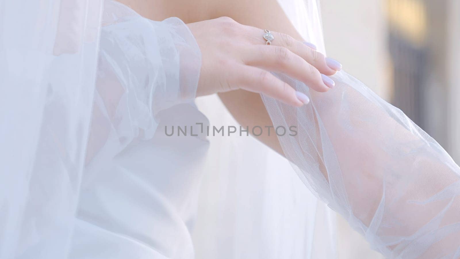 Close-up of bride with veil and white outfit. Action. Beautiful delicate details of bride's outfit. White veil on young bride.