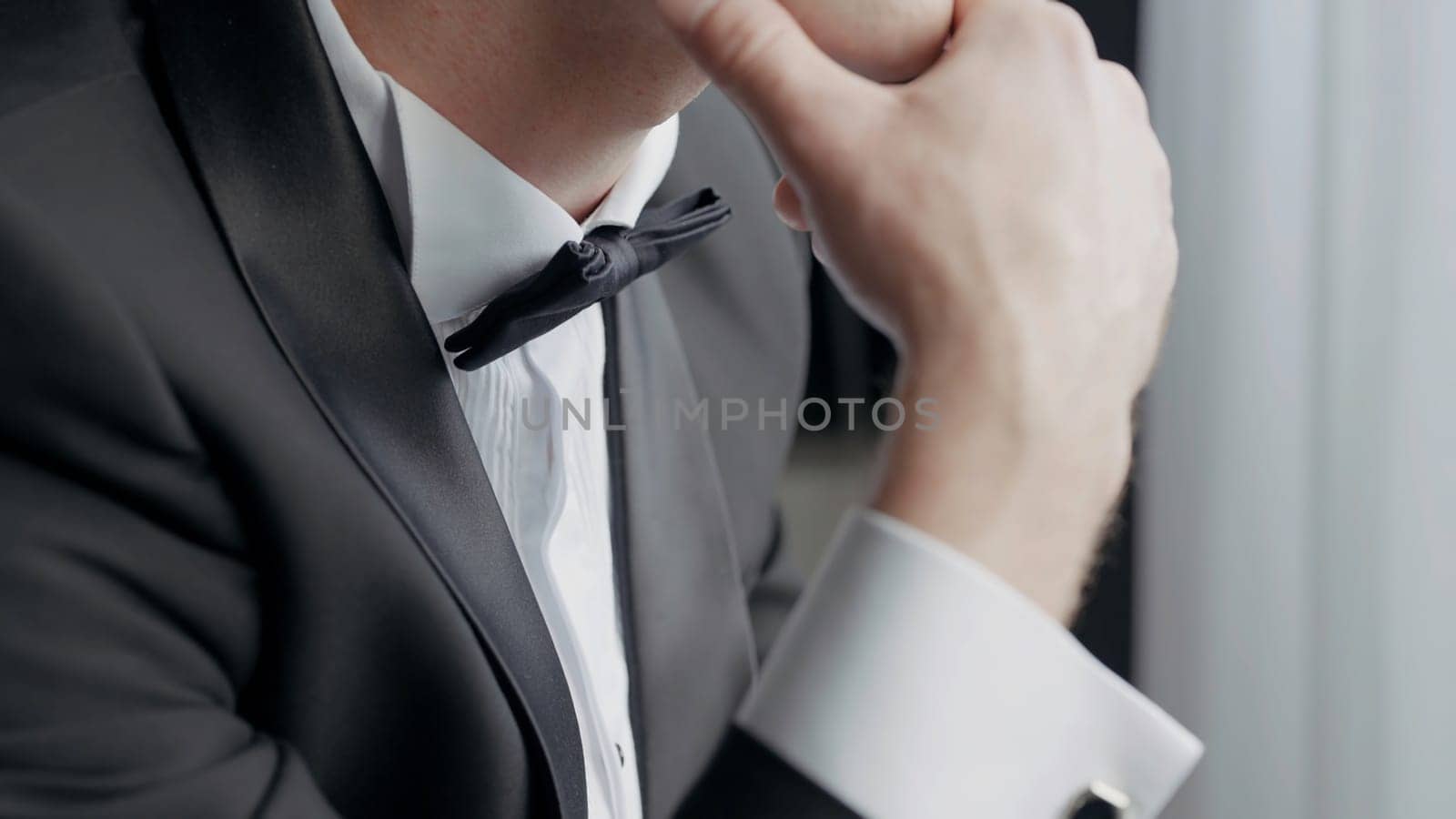 Close up of a man dressed in black and white suit with a bow tie. Action. Details of a worried male groom before the wedding ceremony. by Mediawhalestock