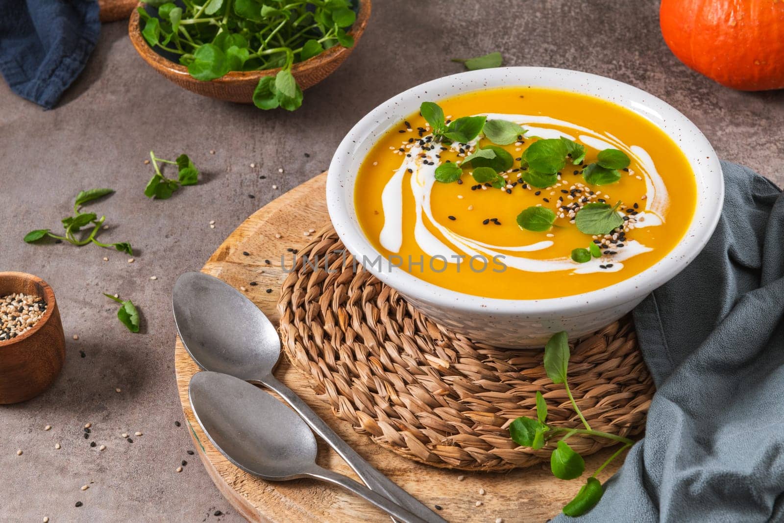 Delicious homemade creamy pumpkin soup with cream with sesame seeds and watercress.