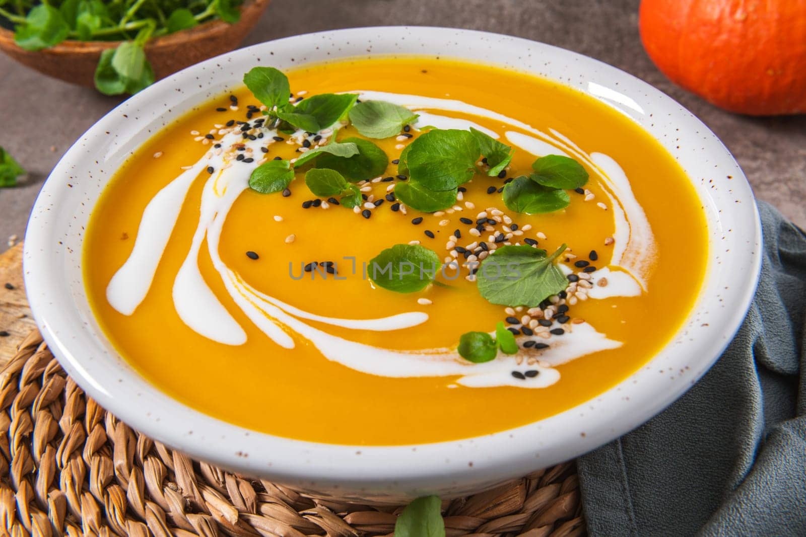 Delicious homemade creamy pumpkin soup with cream with sesame seeds and watercress.