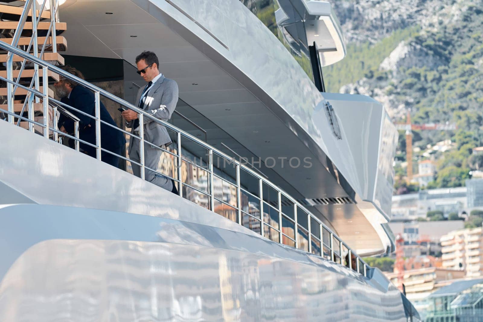 Monaco, Monte Carlo, 27 September 2022 - handsome man with smartphone on deck of mega yacht, Invited wealthy clients inspect megayachts at the largest fair exhibition in the world yacht show by vladimirdrozdin