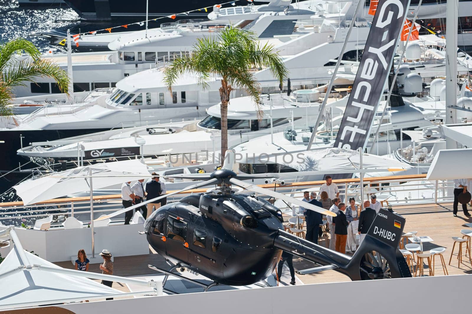 Monaco, Monte Carlo, 27 September 2022 - Rich clients visitors examine a helicopter standing on the deck of a yacht club, the largest fair yacht show, port Hercules, yacht brokers, sunny weather. High quality photo