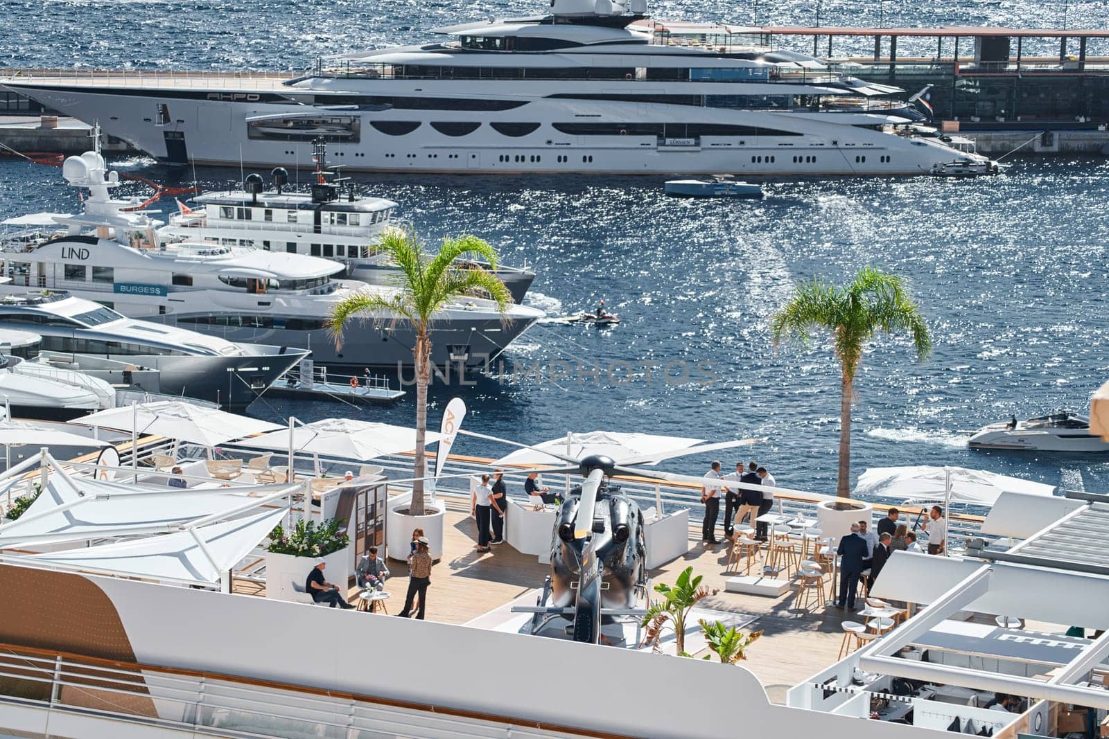 Monaco, Monte Carlo, 27 September 2022 - Rich clients visitors examine a helicopter standing on the deck of a yacht club, the largest fair yacht show, port Hercules, yacht brokers, sunny weather by vladimirdrozdin