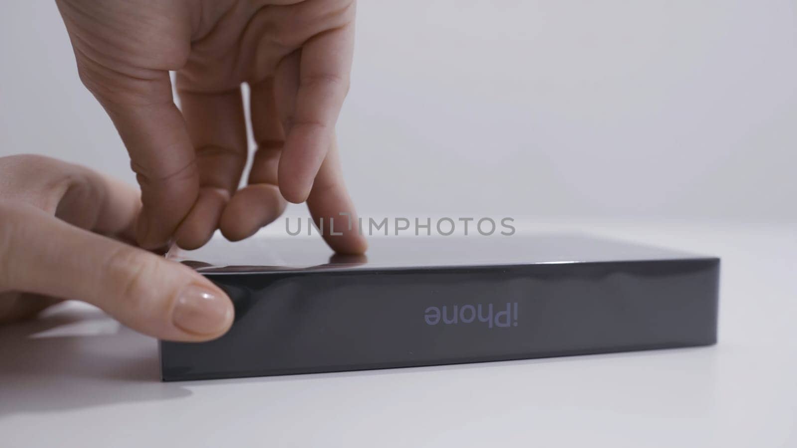 MOSCOW, RUSSIA-NOVEMBER, 2020: Close-up unboxing of iPhone. Action. Close-up of man opening box from new iPhone. Man's hand peels off film from box with new smartphone.