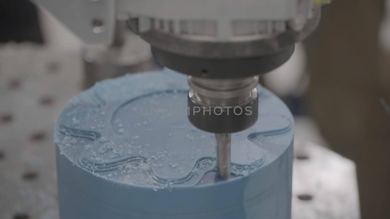 Industrial milling machine at work with blue wax candle blank. Close up of milling machine making beautiful ornament on wax figure or candle.