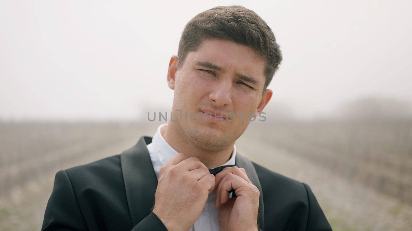 Young posing man in a suit. Action.Handsome man in a glamorous suit fixes his bow tie and looks at the camera. High quality 4k footage