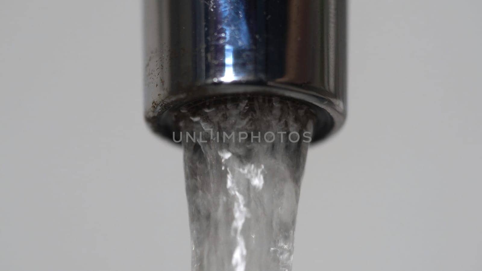 Extreme close up of the water flowing from the faucet. Chrome water tap spout with flowing fresh water.