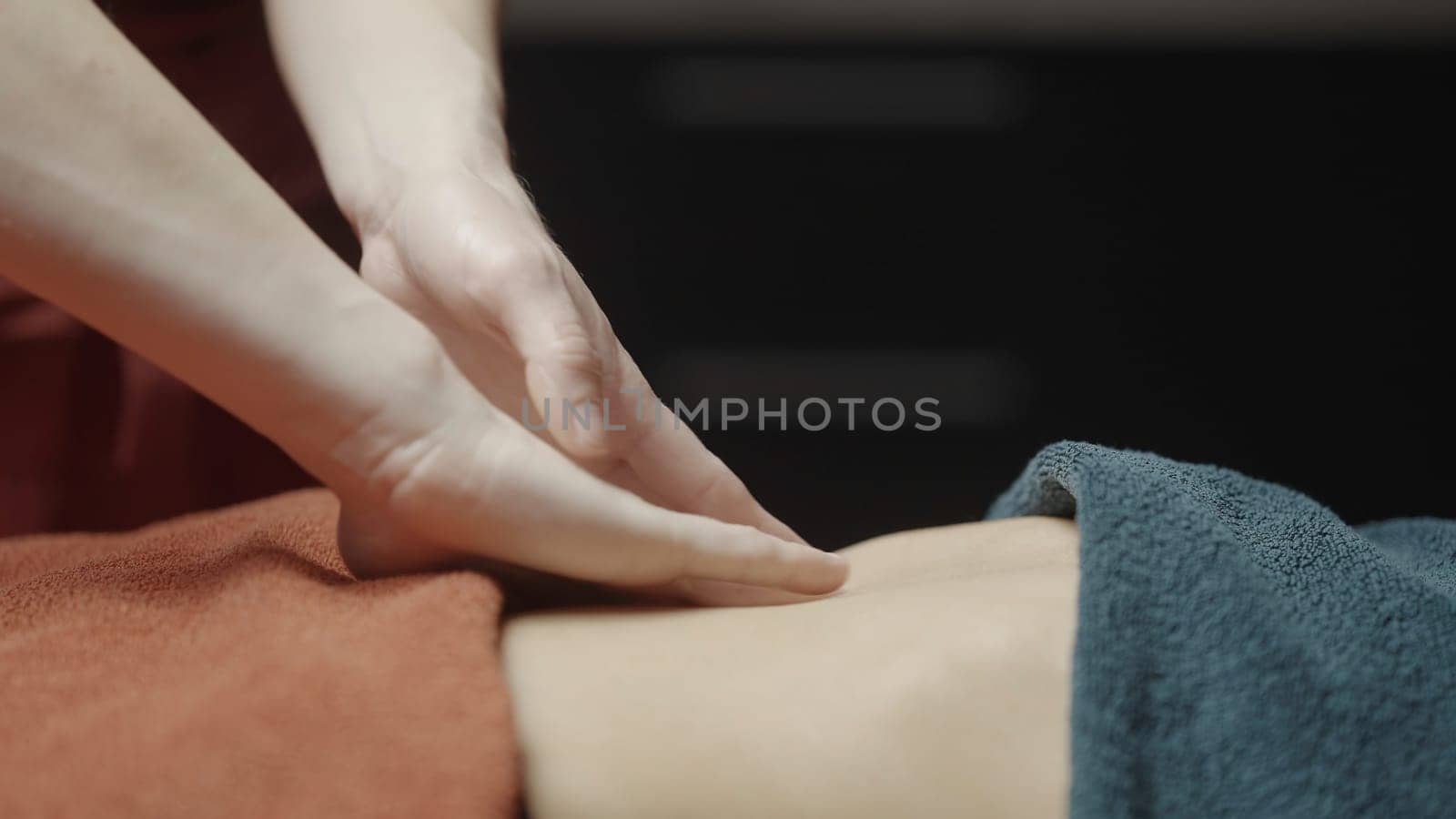 Close-up of masseur smoothly doing massage. Action. Gentle smoothing movements of masseur. Masseur does relaxing massage. Spa salon.