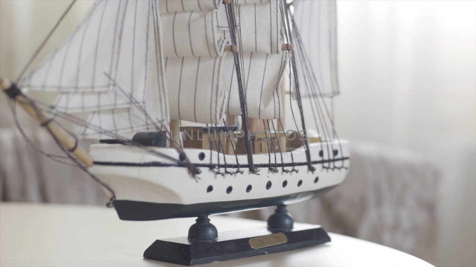 Wooden ship toy model standing on a wooden table in light room, hobby concept. Close up of the sailing ship small figure.