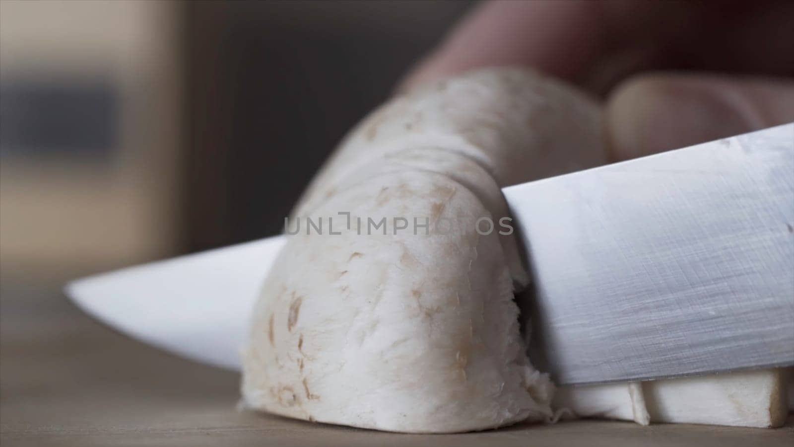 Pieces of champignons, close up of hands cutting the mushrooms into even pieces with a knife, cooking food, vegan, dietary concept. Blade of knife cutting champignons in the kitchen.