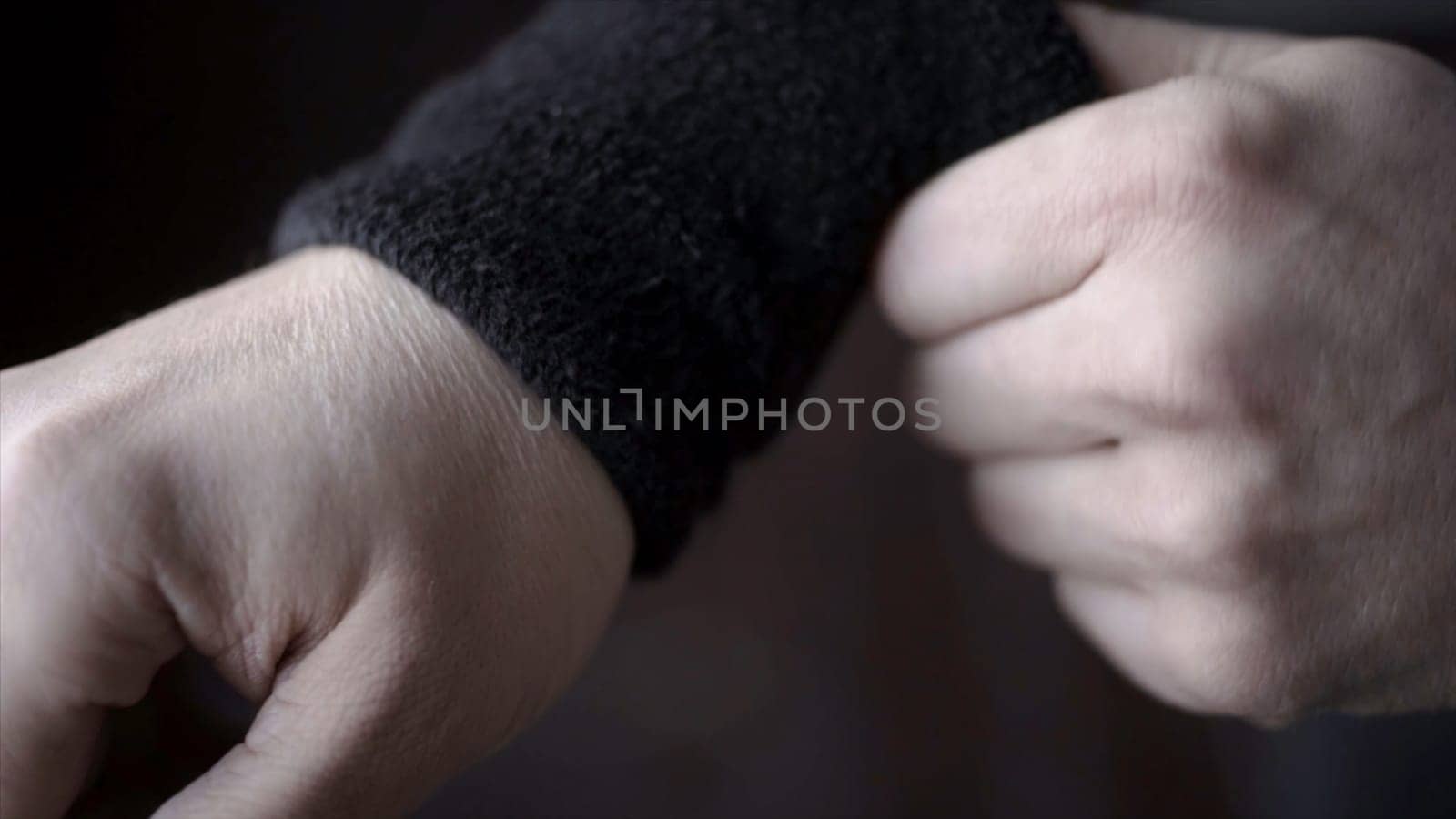 Athlete wears black wristbands. Action. Closeup of athlete adjusts his wristbands on his hands, not to hurt wrist during sports.